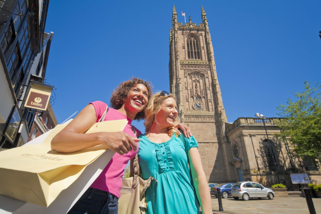 A woman and her daughter with shopping bags in front of Derby Cathedral
